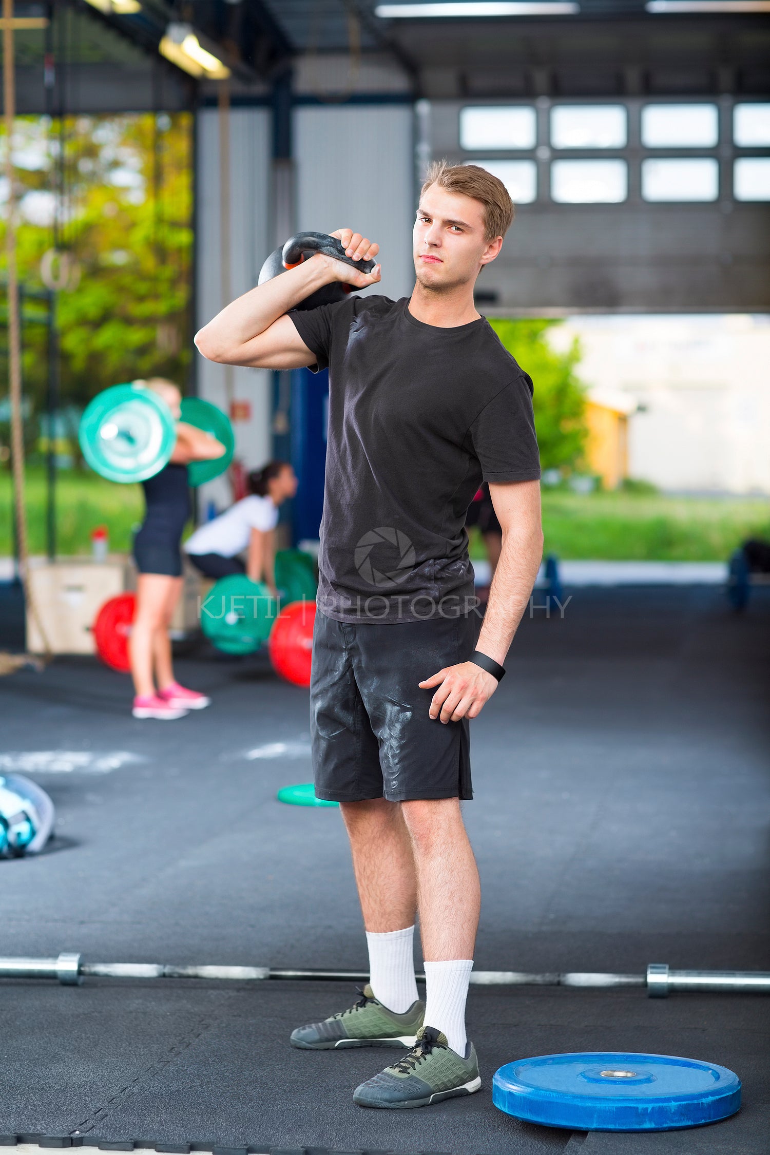 Confident Athlete Carrying Kettlebell In Health Club