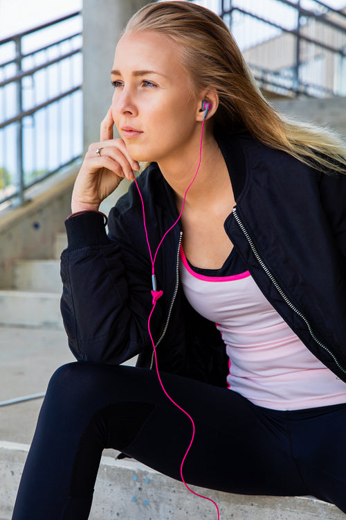 Thoughtful Fit Woman Listening To Music While Sitting On Steps