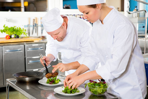 Two chefs prepares steak dish at gourmet restaurant