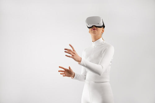 Woman in white wearing VR headset playing around in the virtual reality metaverse
