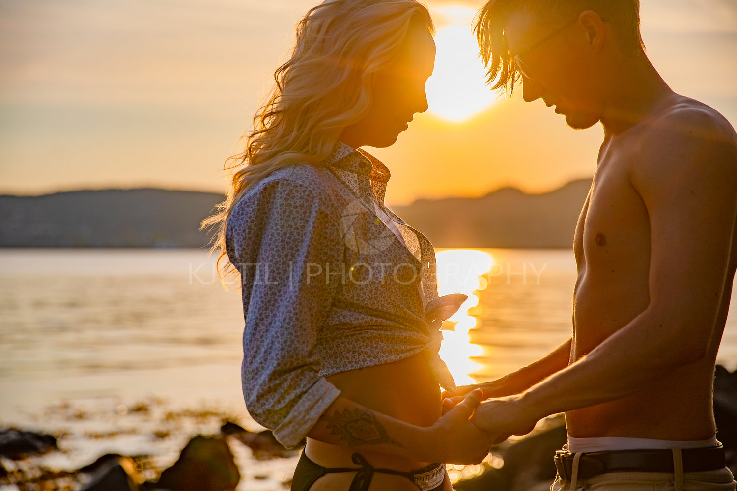 Silhouette of couple in love embracing at the beach against sun
