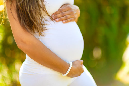 Close-up of pregnant woman standing outdoor holding hands on belly