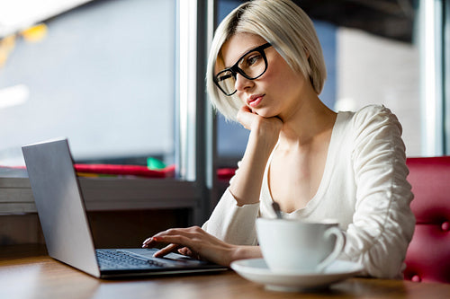 Woman Wearing Glasses While Working On Laptop In Cafe
