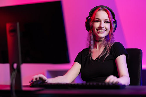 Professional smiling esport gamer girl playing online video game on PC