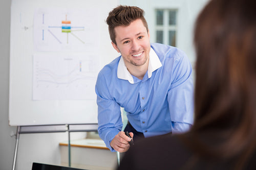Smiling Businessman Looking At Female Colleague In Office