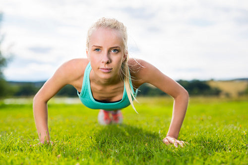 Blonde woman doing push-ups in the park