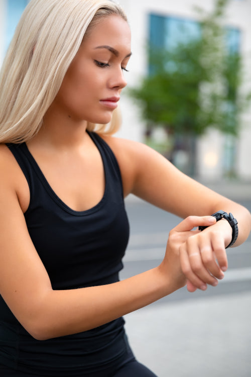 Focused Woman Checking Performance and Tracking On Smartwatch After Exercise
