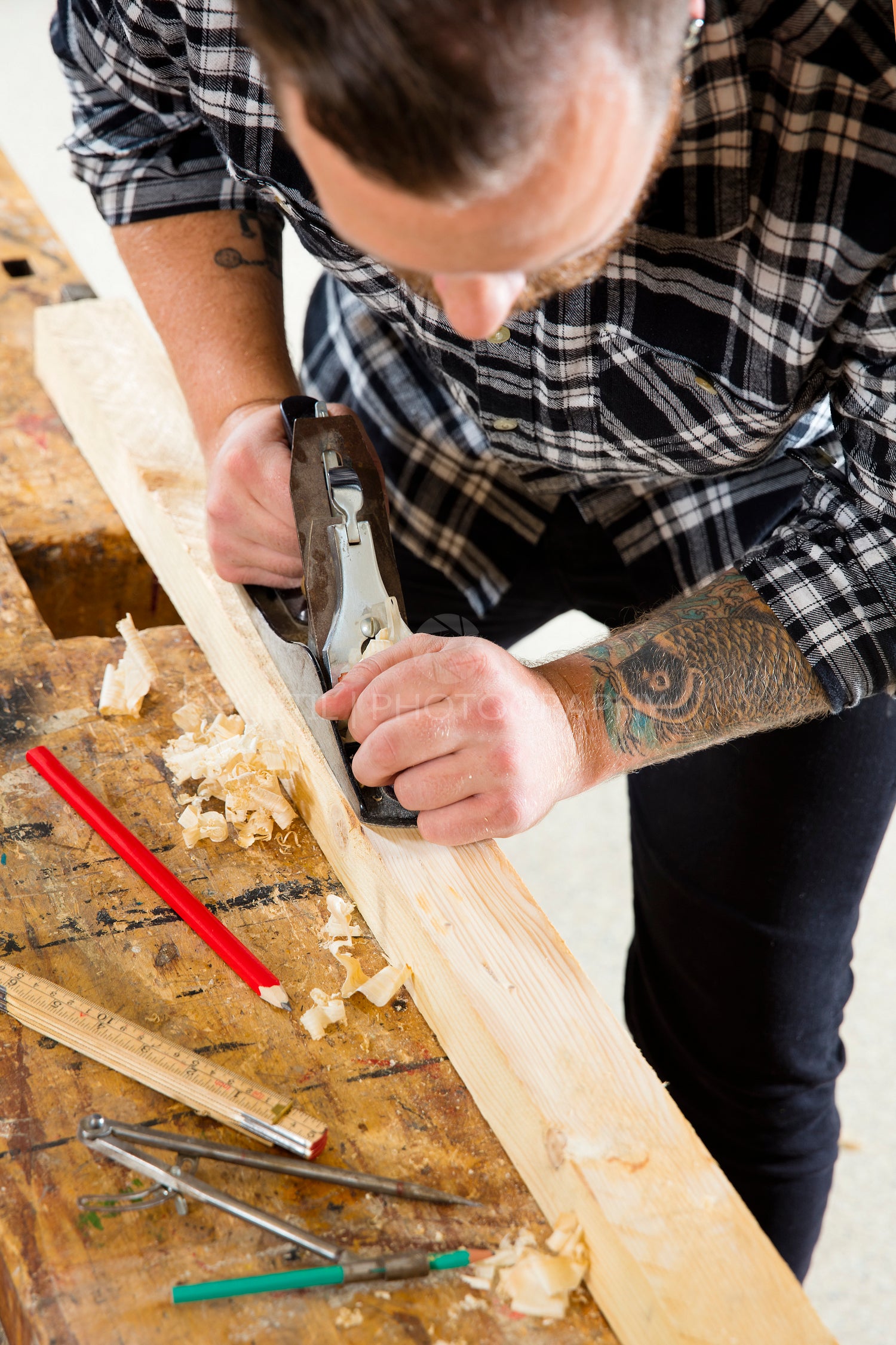 Focused craftsman working with plane on wood plank in workshop