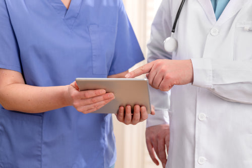 Doctor and nurse discussing patients tests at tablet computer in hospital