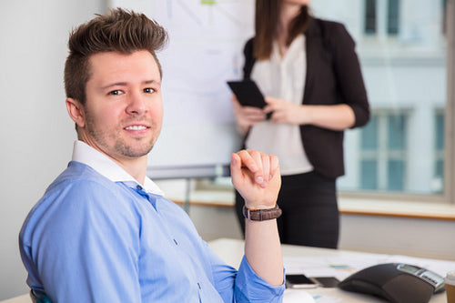 Confident Businessman Smiling While Colleague Standing At Office