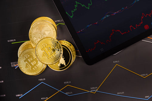 Crypto coins near digital tablet over graph