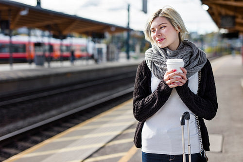 Woman drinking coffee while she waiting for the train