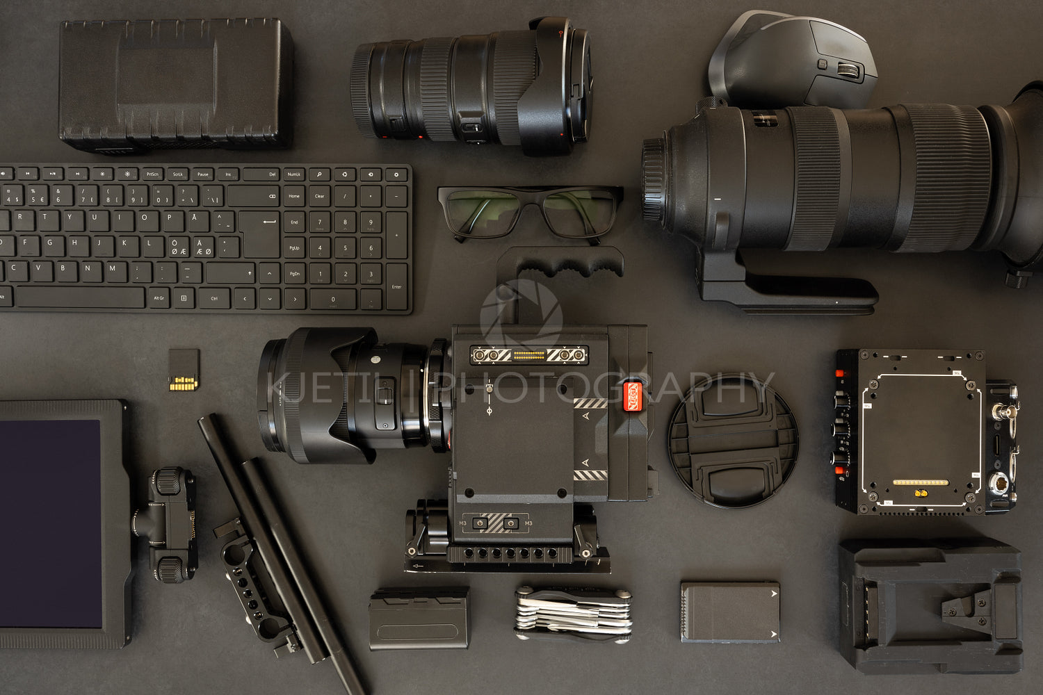 Flat lay of filming equipment with keyboard and eyeglasses on table