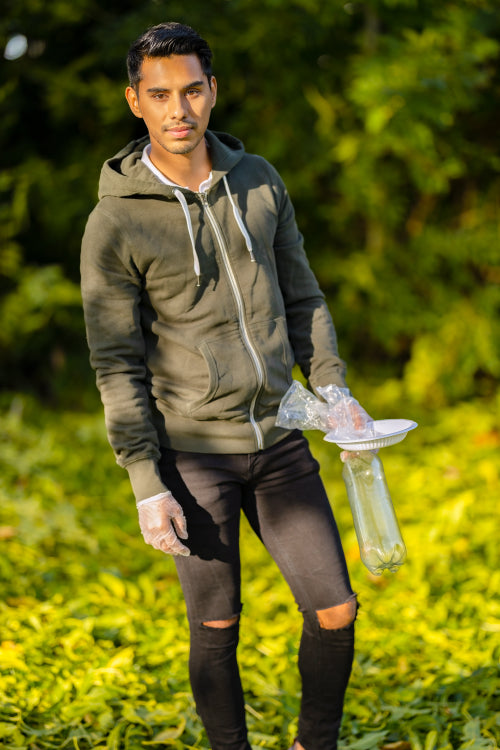 Full length portrait of committed volunteer cleaning garbage on grass in nature