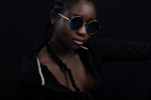 Confident and cool woman with dark skin wearing round sunglasses