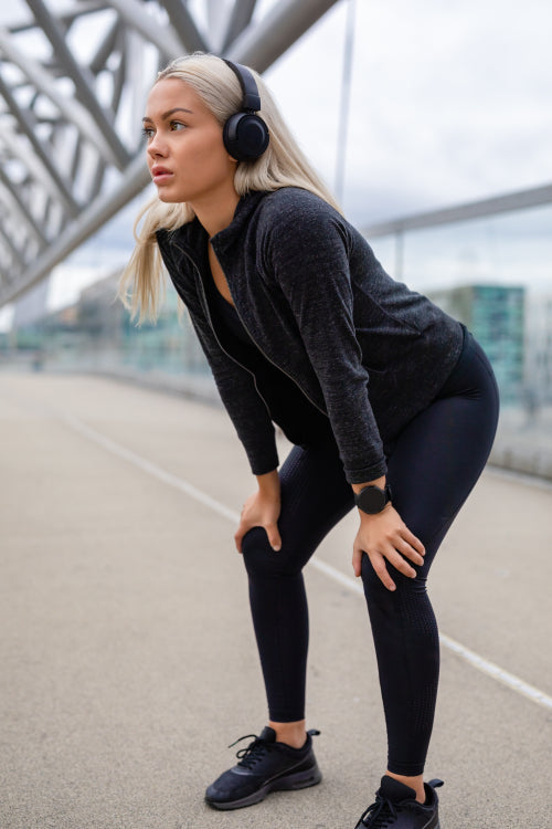 Female Jogger Resting With Hands On Knees After Workout