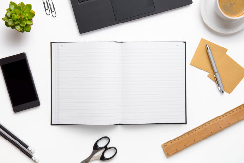 Open Diary Surrounded With Office Supplies On White Desk