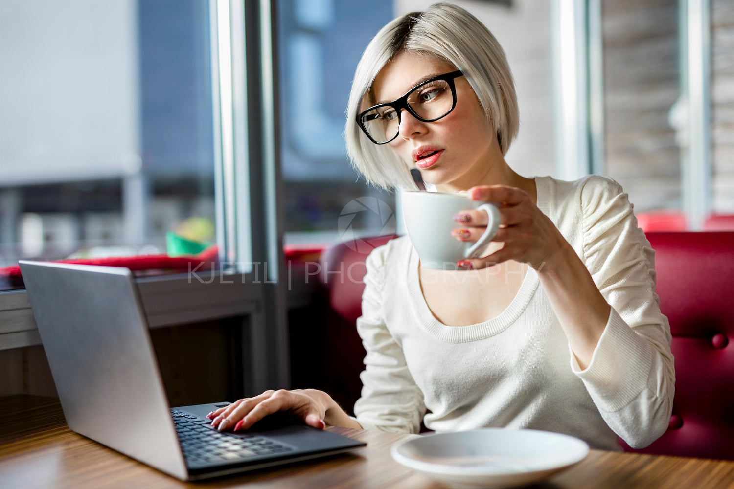 Woman Having Coffee While Working On Laptop In Cafe