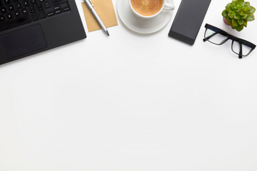 Laptop With Coffee Cup, Eyeglasses And Smartphone On White Desk