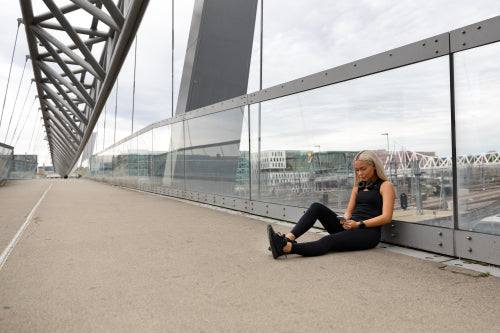 Runner Sitting On Bridge After Workout and Using Smart Phone