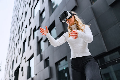 Woman Wearing Virtual Reality Glasses In Front Of Future Looking City Building