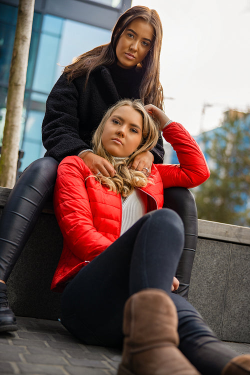 Portrait Of Fashionable Friends Sitting Togehter In City
