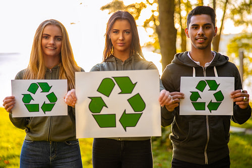 Young environment protective volunteers holding recycling symbol placard