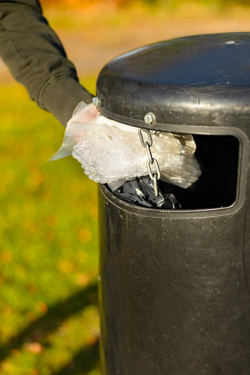 Volunteer putting plastic trash in garbage bin at park