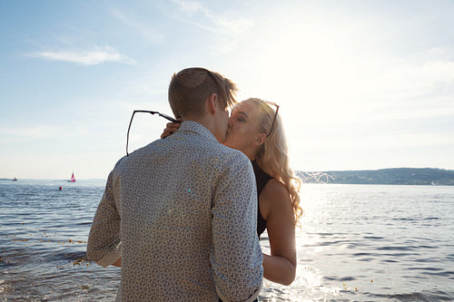 Romantic couple kissing on beach against the sun