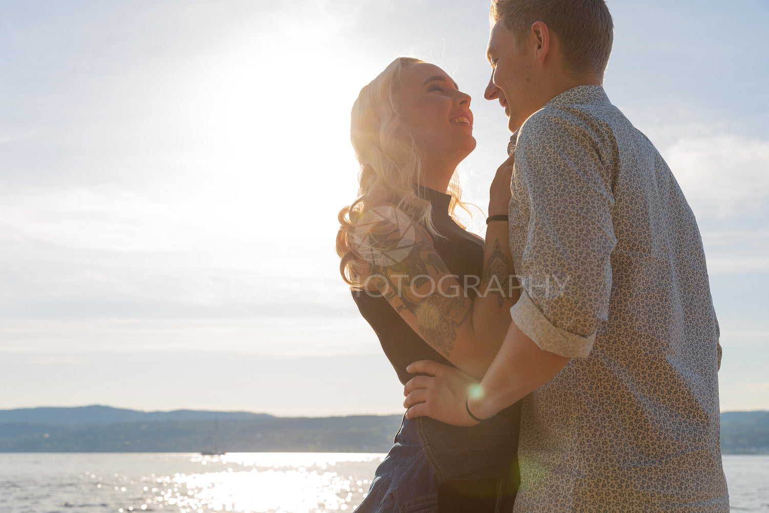 Smiling couple in romantic embrace on beach at summer
