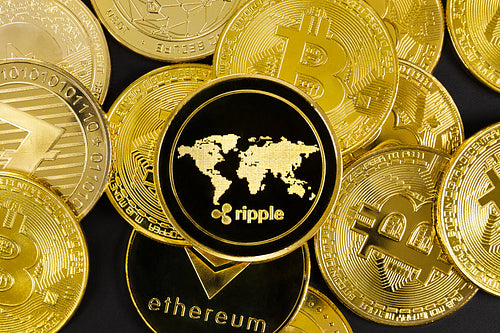 Close-up of Ripple coin on top of various golden cryptocurrencies