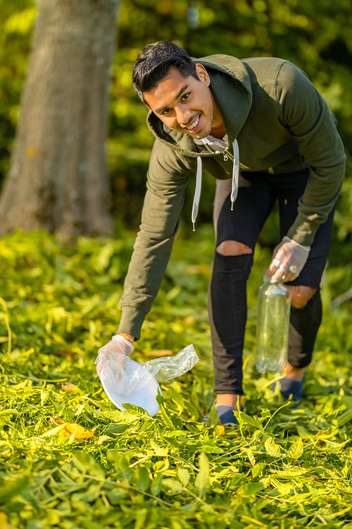 Close-up of dedicated volunteer cleaning garbage on grass in nature