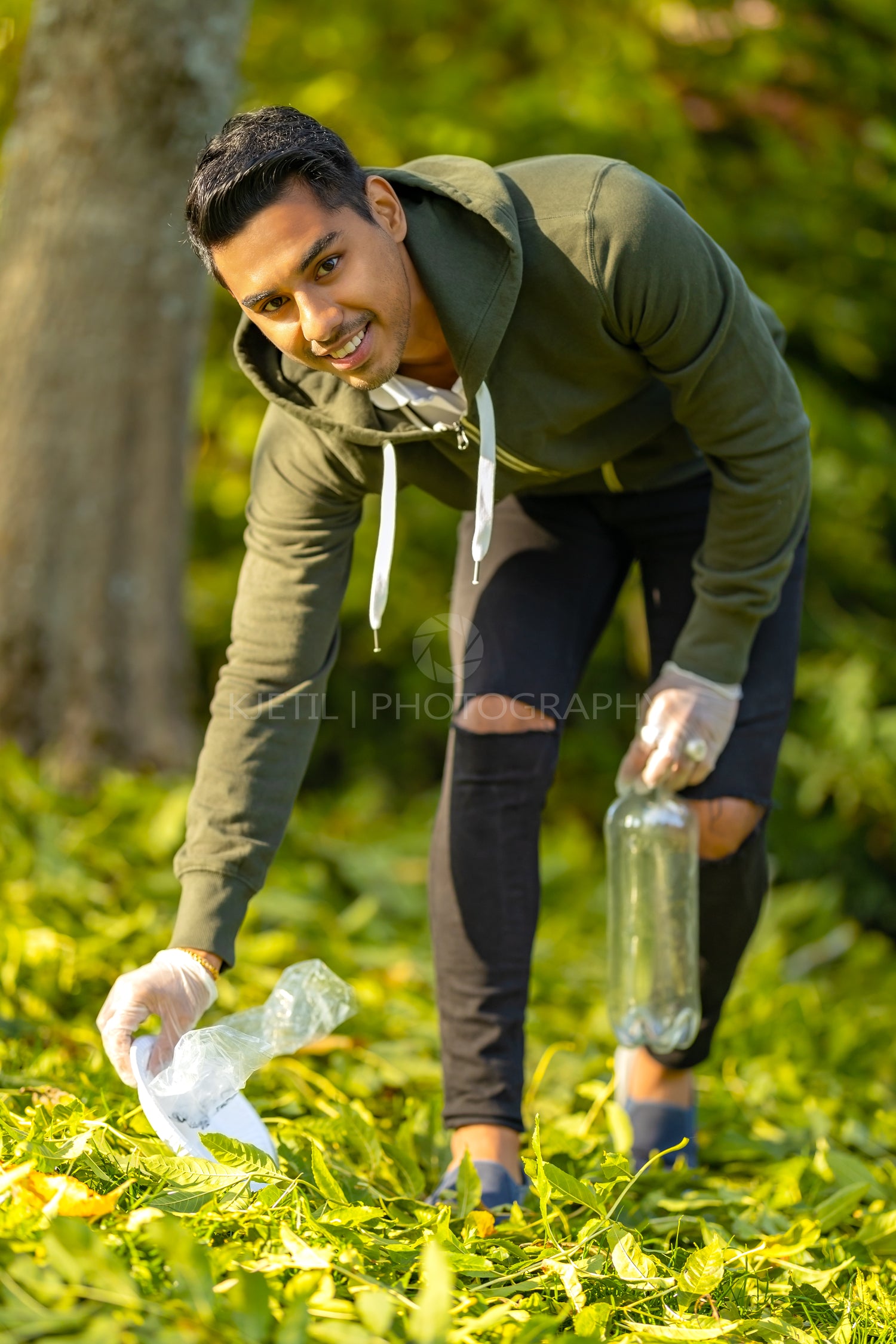 Young committed volunteer cleaning garbage on grass in nature