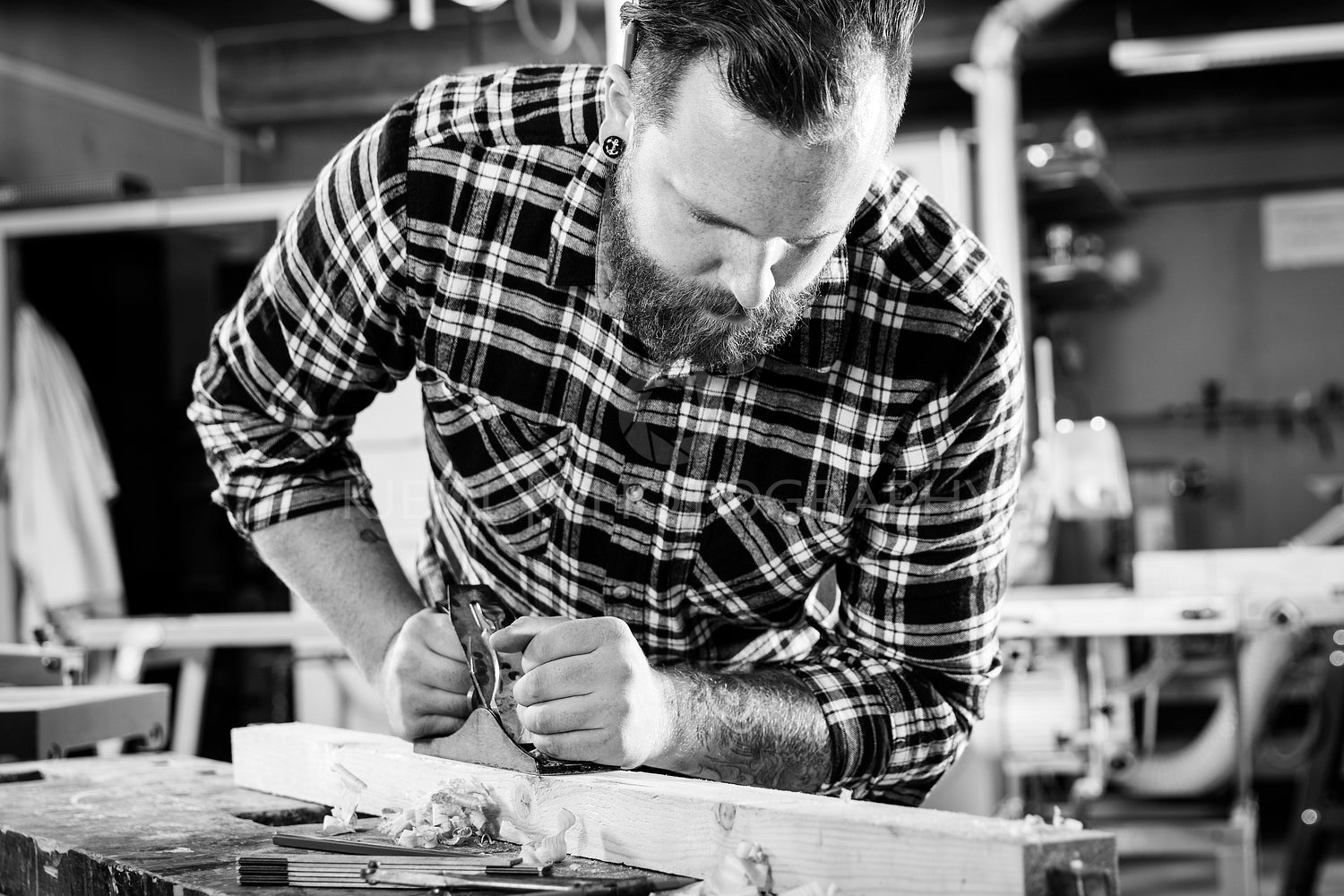 Carpenter work with plane on wood plank in workshop