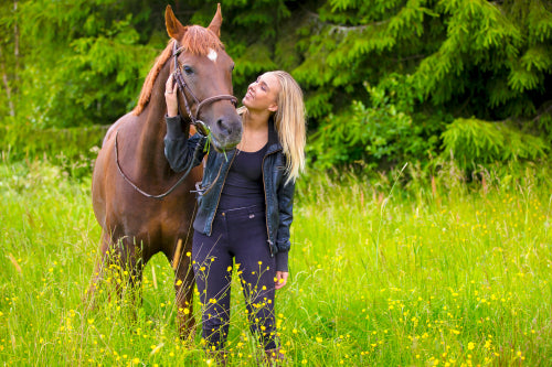 Young woman with her arabian horse standing in the field