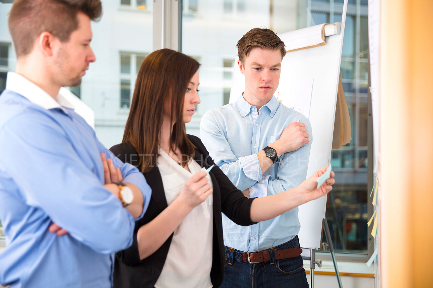 Coworkers With Adhesive Notes Standing In Office