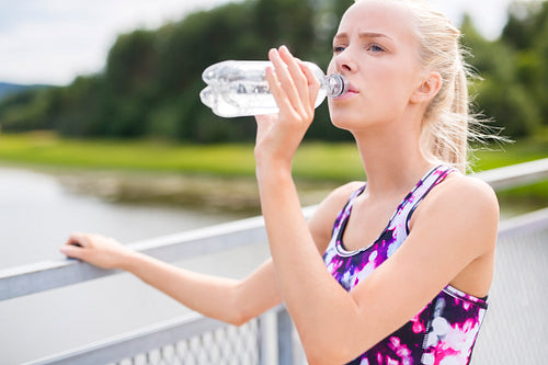 Woman having a break and drinks water after running