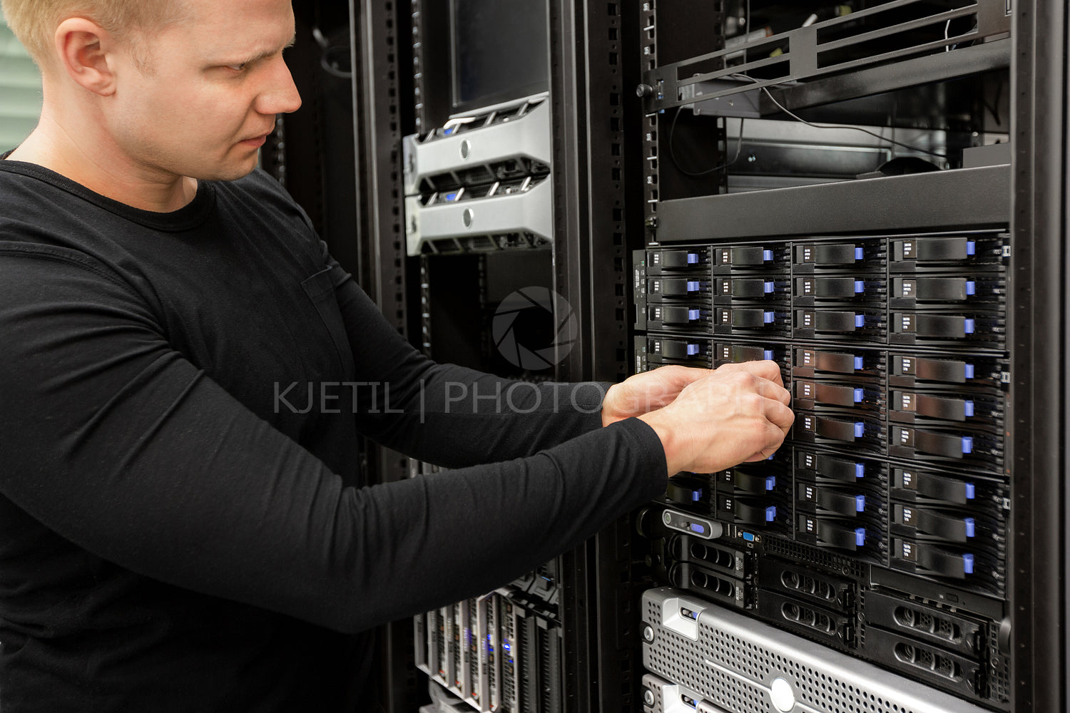 Male Technician Adjusting Hard Drives In SAN At Datacenter