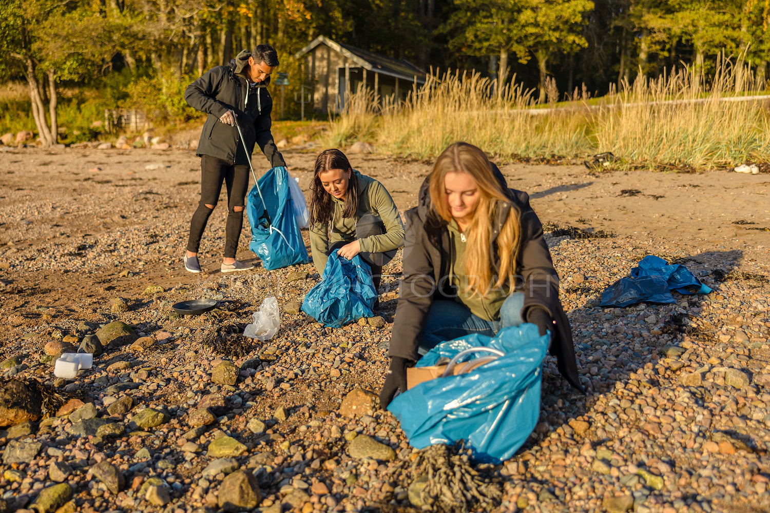 Group of volunteers picking up plastic garbage at beach and from the sea