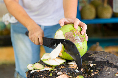 Woman cutting fresh coconut at the market