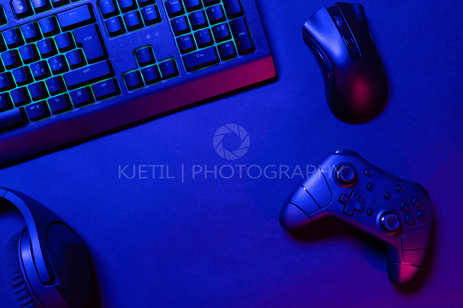 Green lit keyboard on blue lighted gaming gadgets on desk
