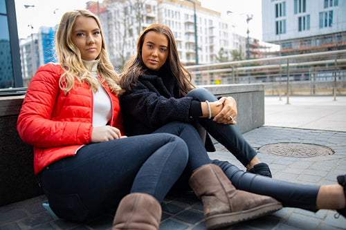 Portrait Of Two Confident Female Friends Sitting In City