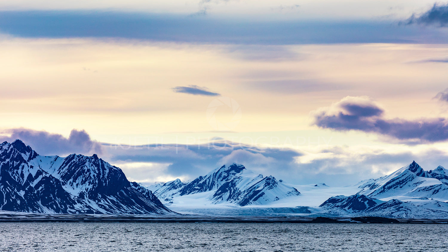 Clouds over snowy mountains and glacier in the arctic