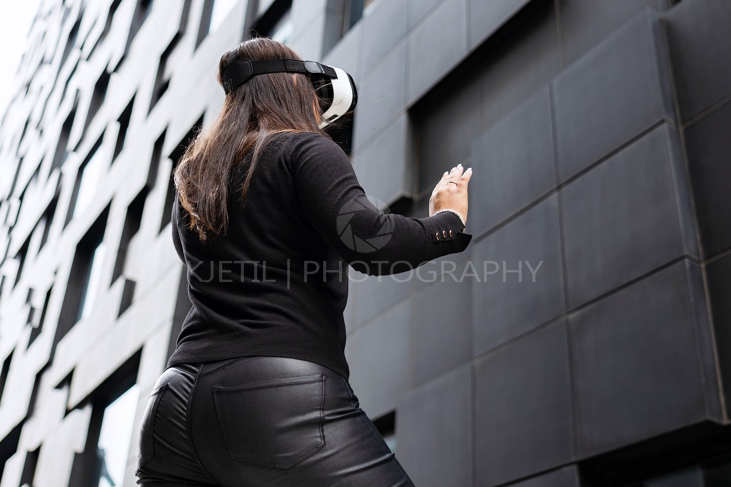 Back Of Woman Wearing Virtual Reality Technology Glasses Against Modern Building