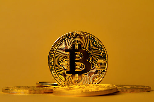 Closeup of gold bitcoin on yellow backgound