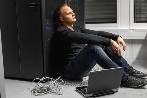 Exhausted Mid Adult Male IT Engineer Against SAN At Datacenter