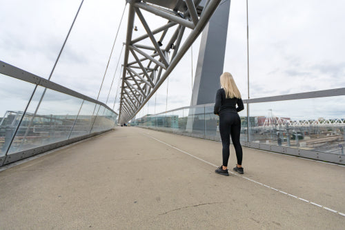 Fitness woman runner Standing On Bridge in Modern Looking City
