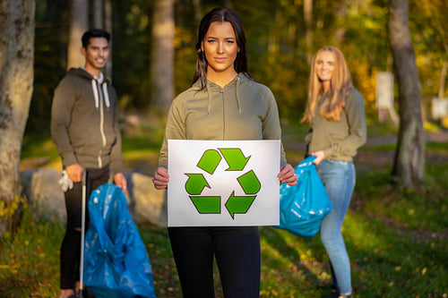 Confident volunteer woman holding recycling symbol placard