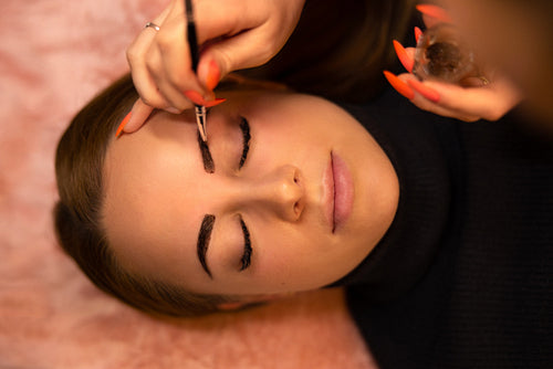 Beautician Applying Dye On Female Customer's Eyebrow