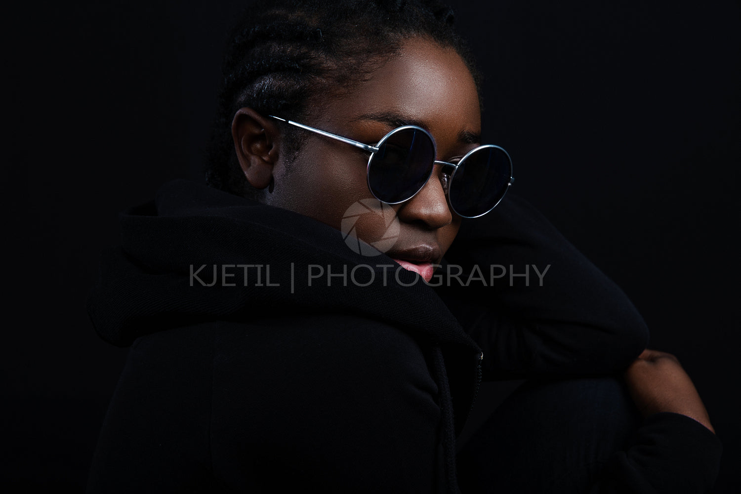 Cool woman sitting with dark skin wearing round sunglasses